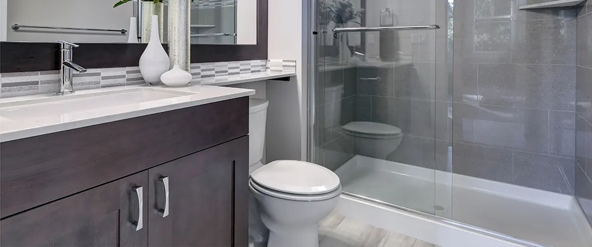 A bathroom renovation cost in Mississauga with a brown vanity, glass shower, and porcelain tiles