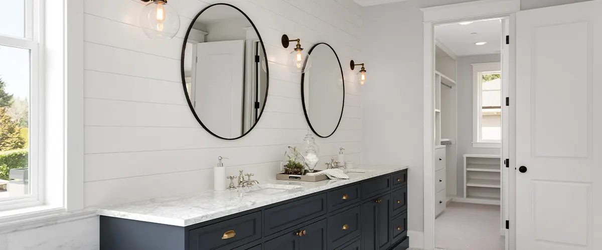 A bathroom renovation with round mirrors and a black double vanity