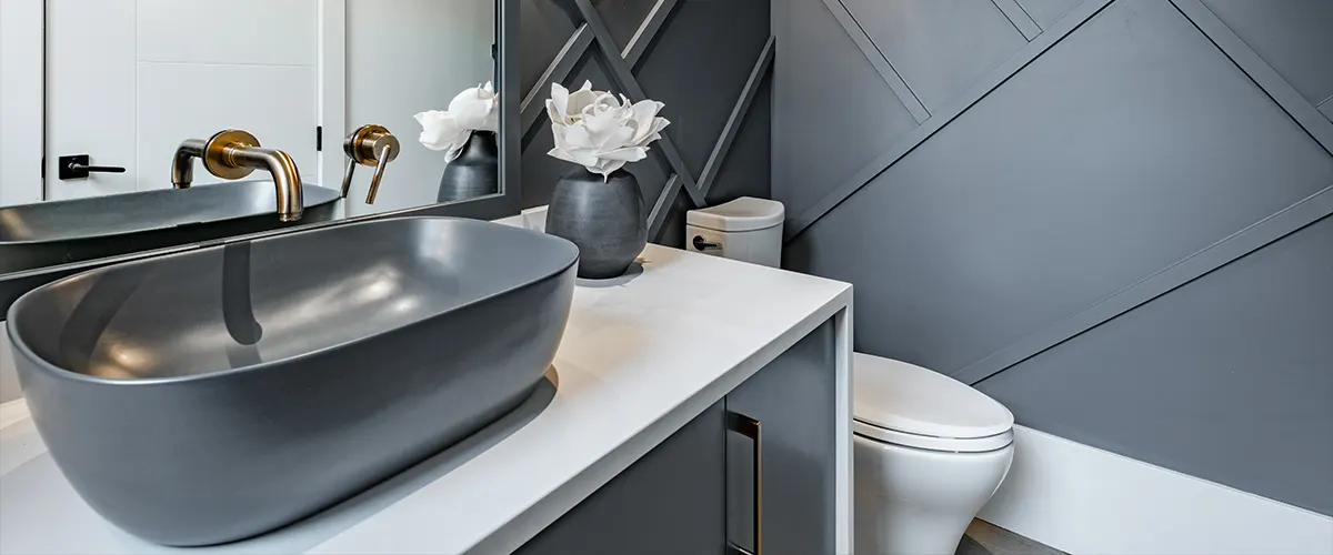 A powder room with gray walls and a big gray sink