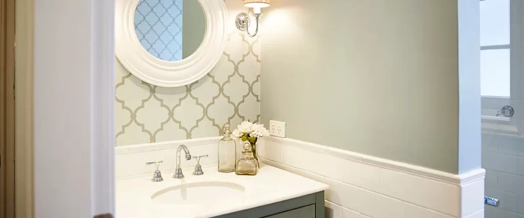 A pastel powder room with a small round mirror