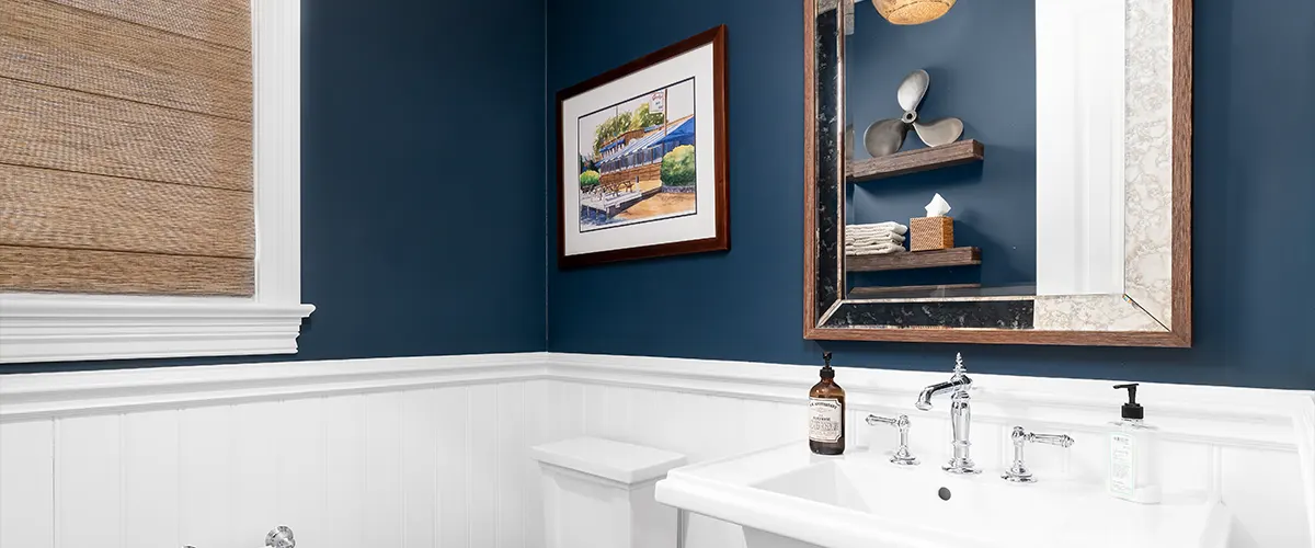 A warm brown color in a powder room with blue walls and a painting near the mirror