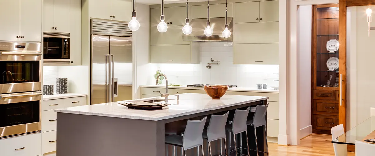 A remodeled kitchen with beige cabinets and yellow overhead lights