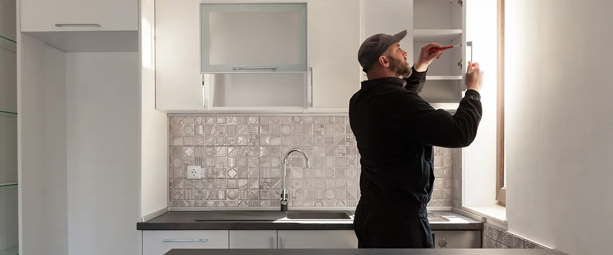 A contractor installing kitchen cabinets in a renovated kitchen