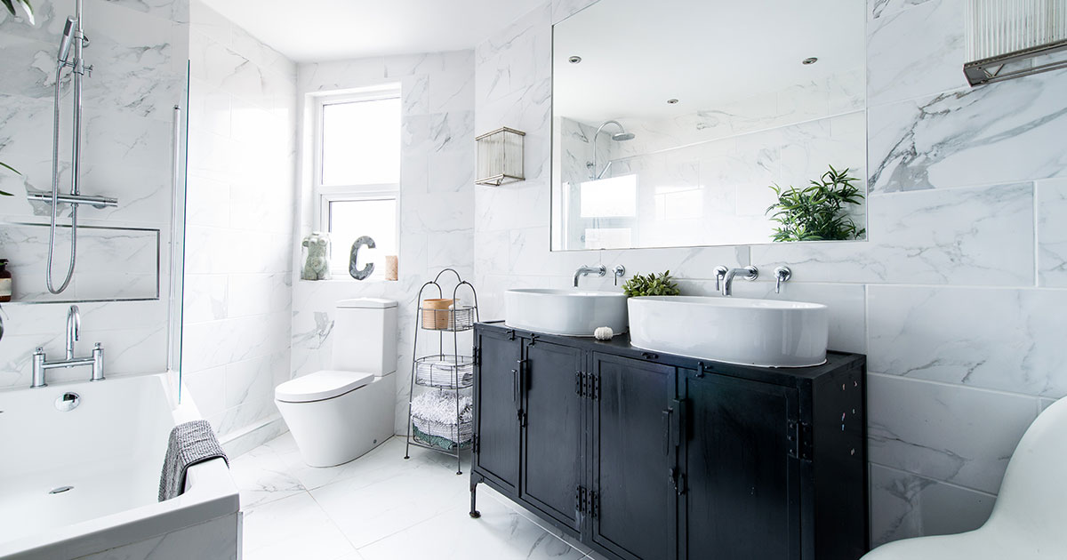 A white bathroom with a dark vanity with grout on tiles and caulk on sink