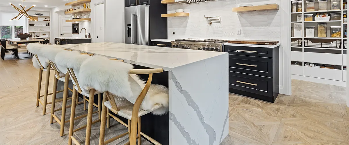 A kitchen island with quartz counter and faces in a kitchen with golden features