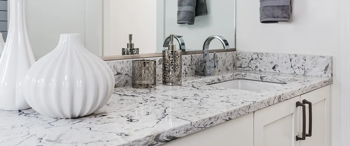 A granite countertop with a white vase and silver fixtures