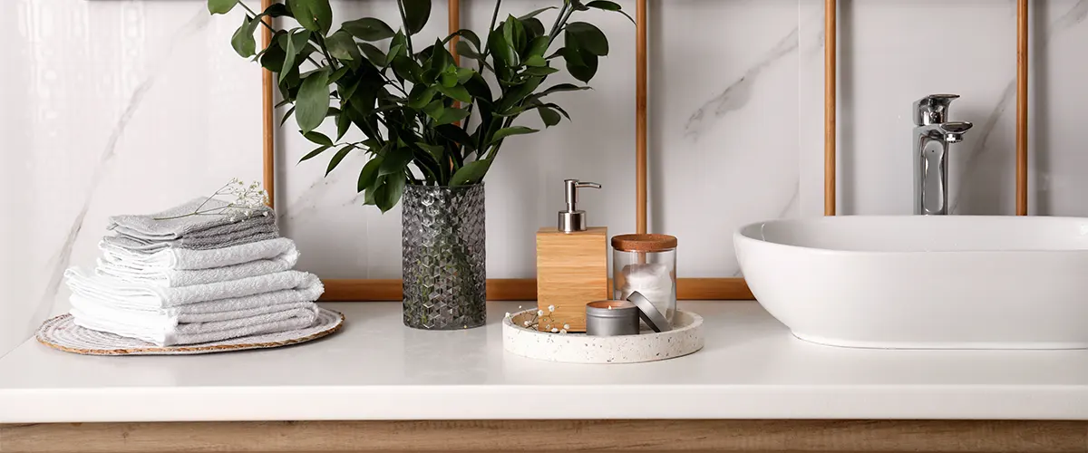 A marble countertop with towels, a vase with a plant, and a sink
