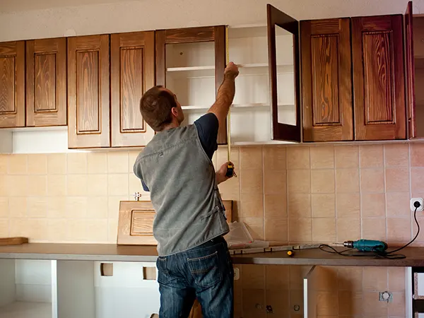 man measuring kitchen cabinets