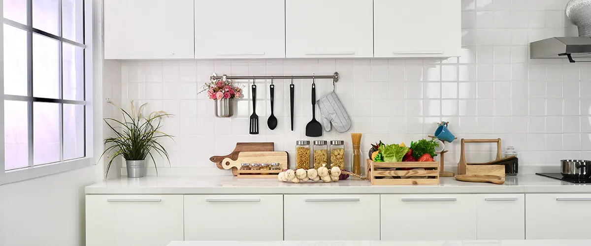 White modern cabinets with horizontal silver pulls and a counter used to store aliments and utensils