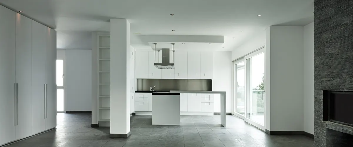 A modern white kitchen with gray floors that resemble concrete