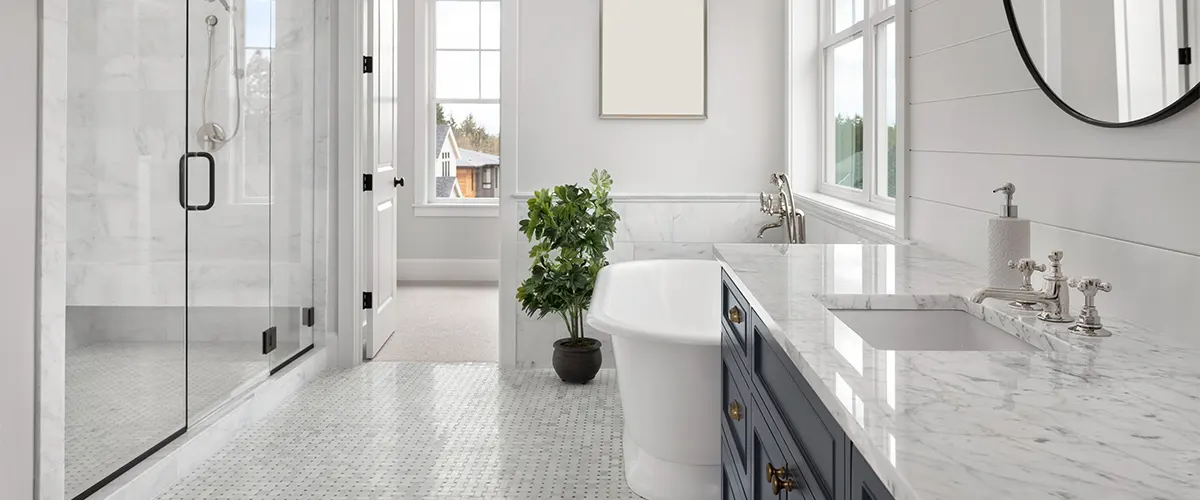 A white bathroom with a double vanity, round mirror, and a plant