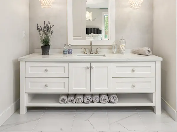 A white vanity with silver hardware and towels underneath it