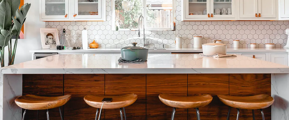 A wooden kitchen island with a quartz counter and wood stools