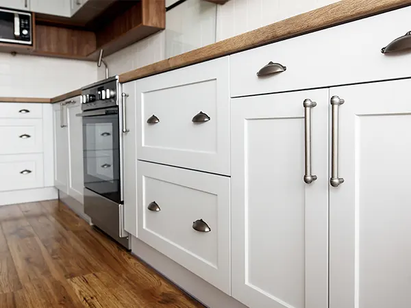 A close up with white kitchen cabinets and silver hardware