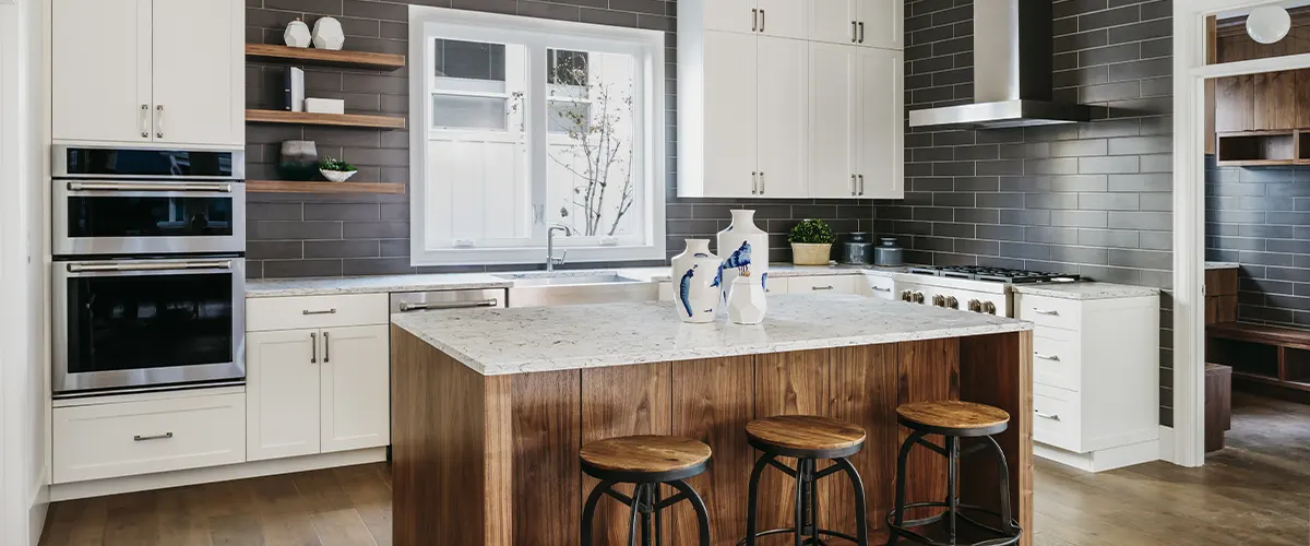 A wood island with a quartz counter and white transitional cabinets