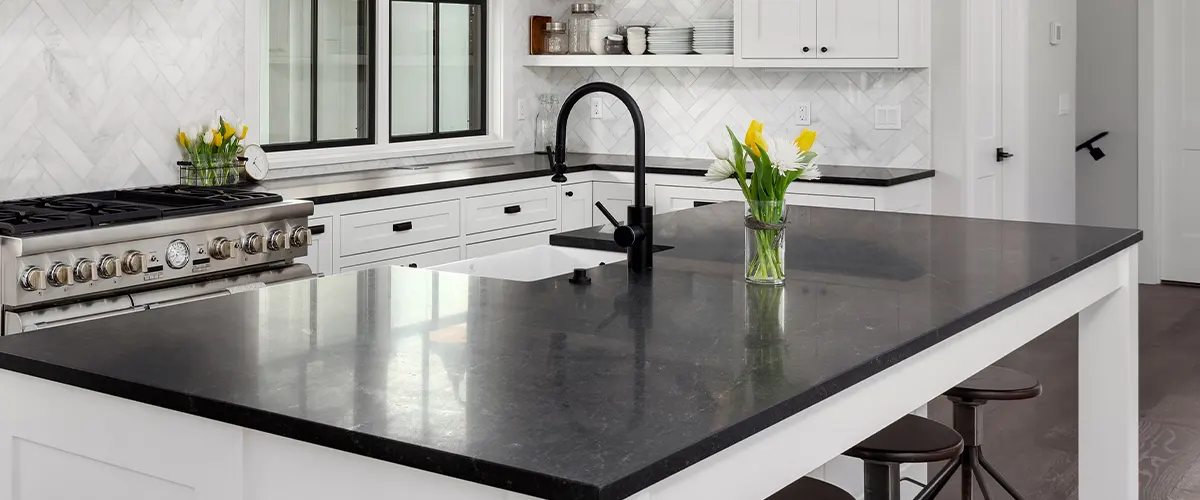A black quartz counter with an undermount sink with black faucet