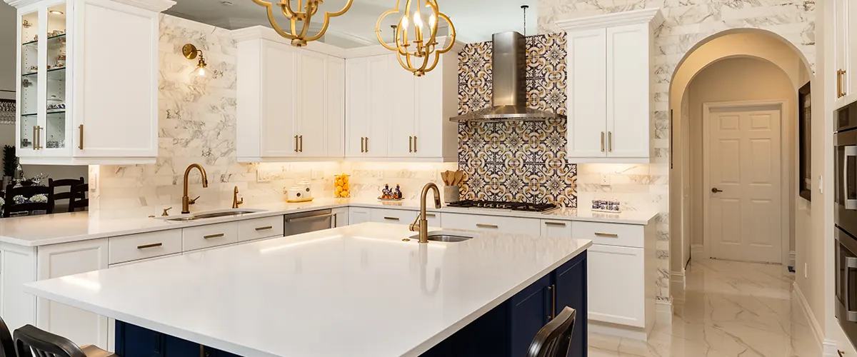 A white counter in a kitchen with decorative backsplash and blue island cabinets