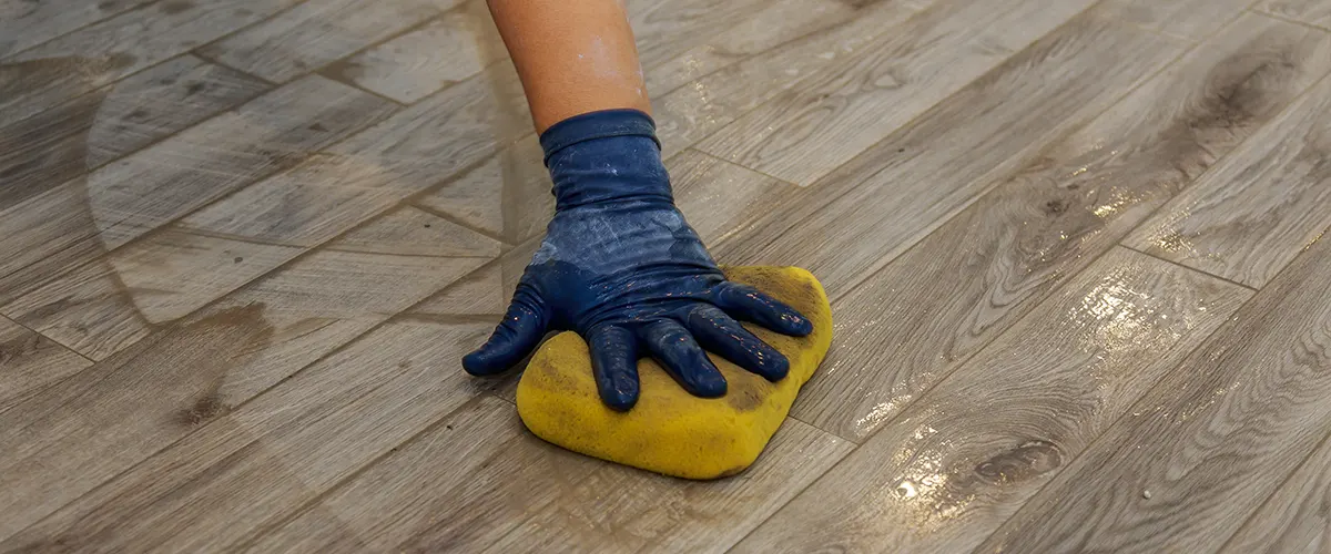 A hand with a blue glove and a yellow sponge maintaining a floating floor
