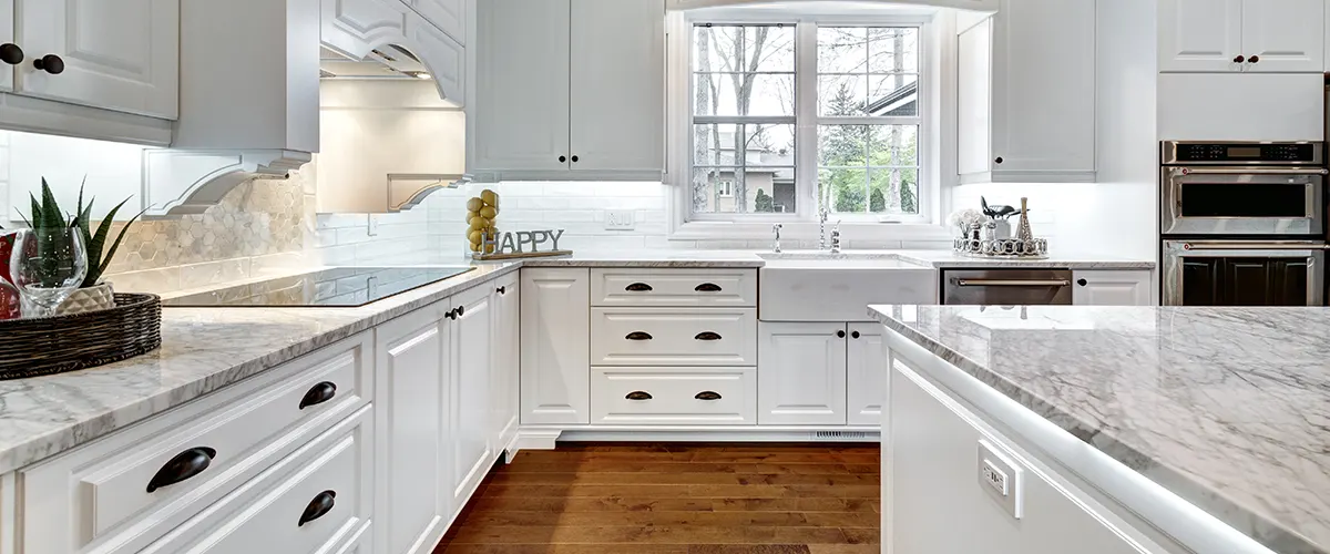 Wood flooring and white cabinets with black pulls and knobs