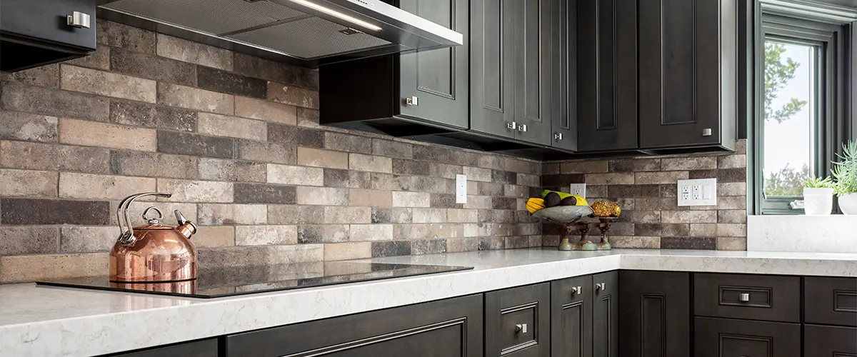 White counters with black cabinets and different hues of backsplash