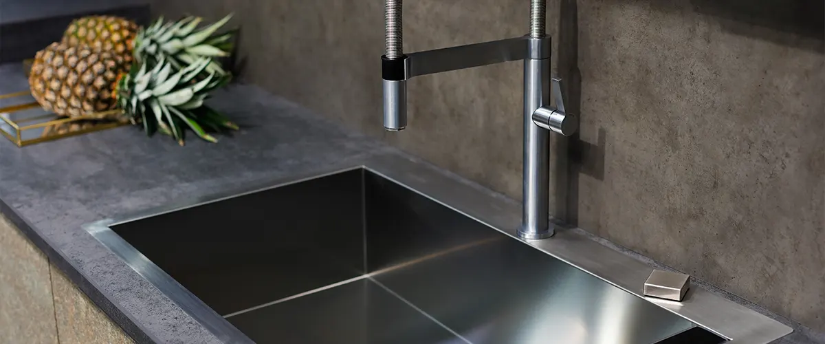 Concrete countertop with black water fixtures and two pineapples