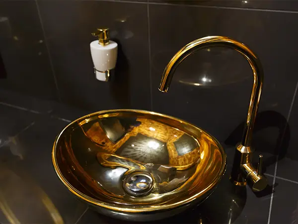 A copper sink in a bath with dark walls