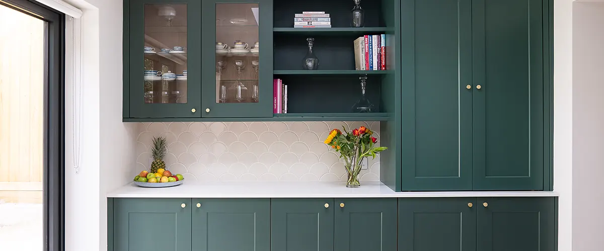 Custom green cabinets with a vase of flowers and open shelving