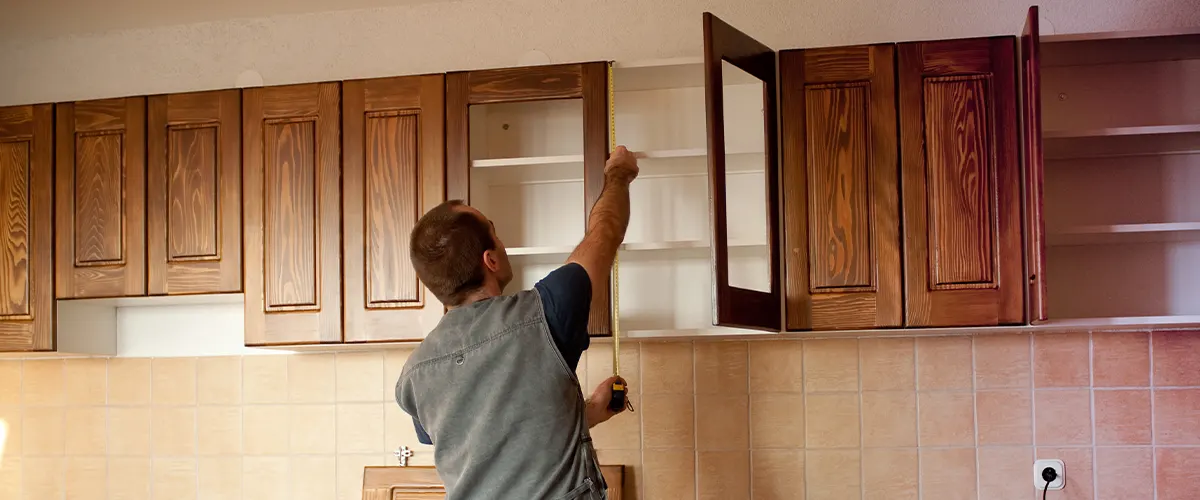 A kitchen remodeler installing wooden kitchen cabinets