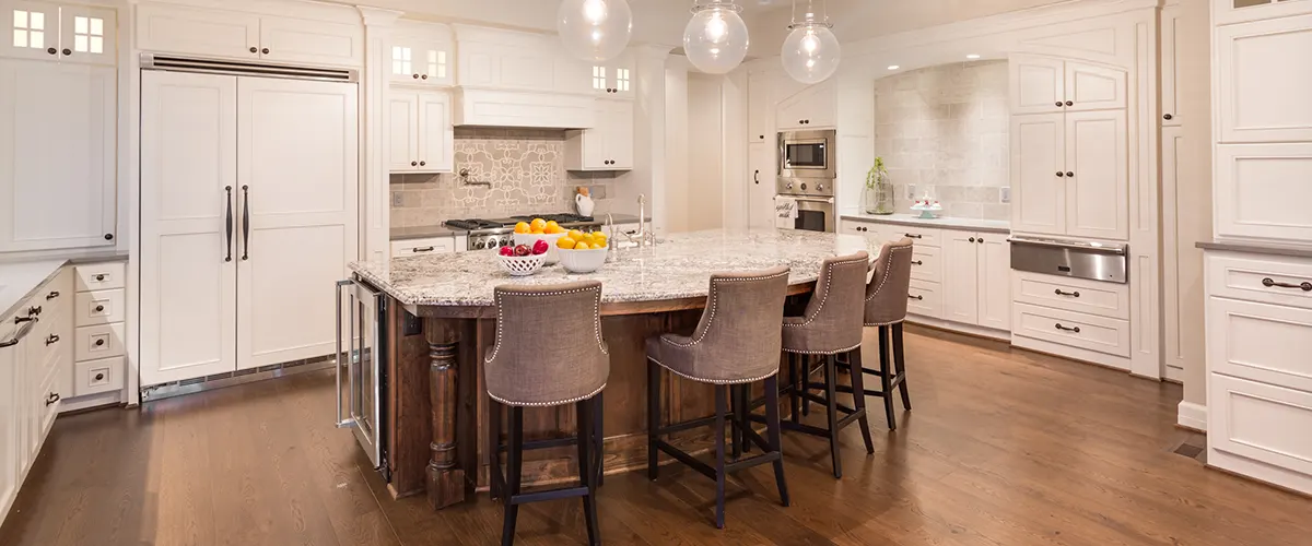 Elegant kitchen with white custom cabinets, crown molding, and custom kitchen island with four chairs