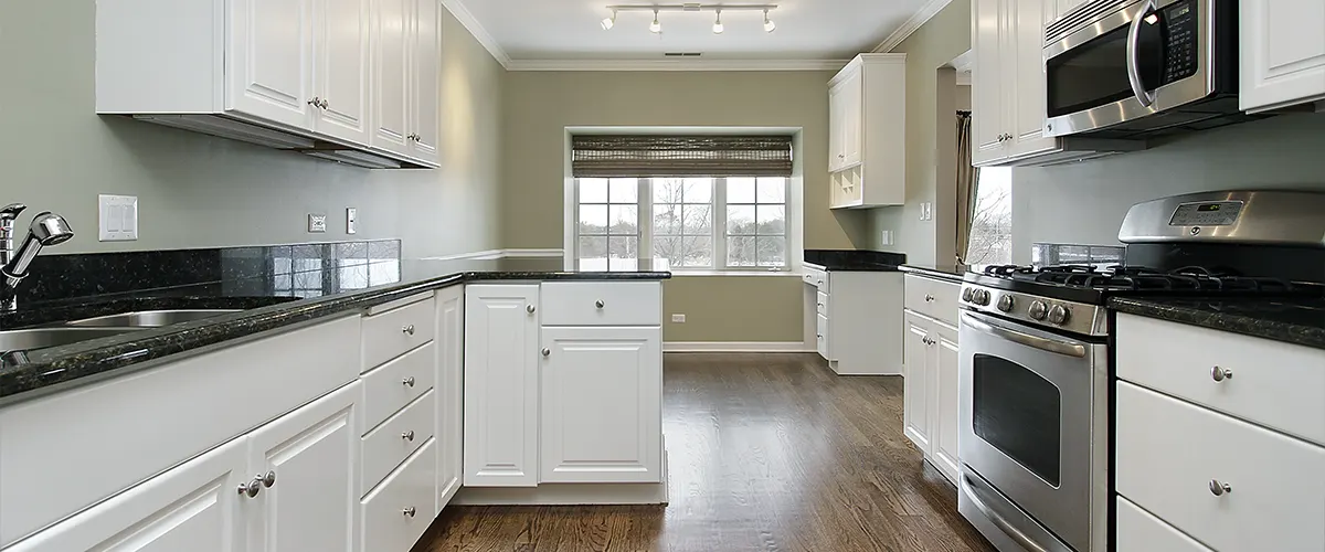 A kitchen range and a microwave in a room with white cabinets