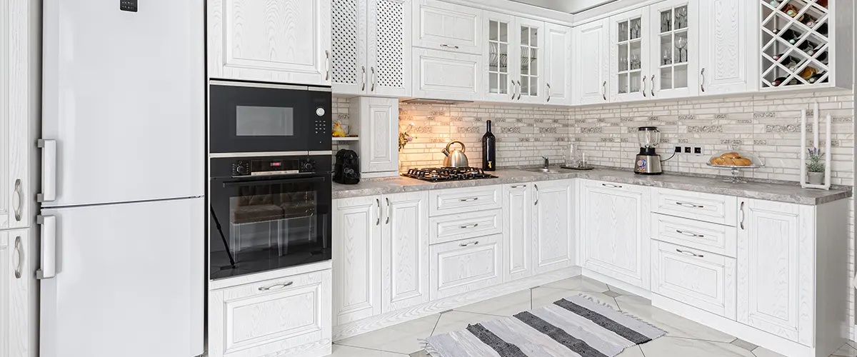 A beautiful white kitchen with transitional cabinets and carpet on the tile floor