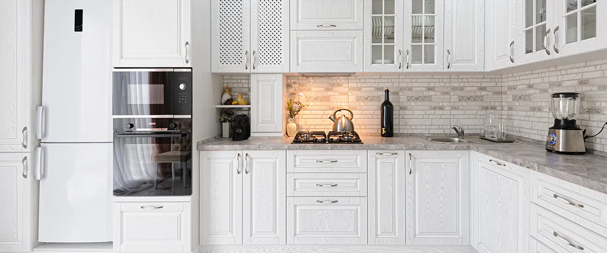 White transitional cabinets with appliances and backsplash