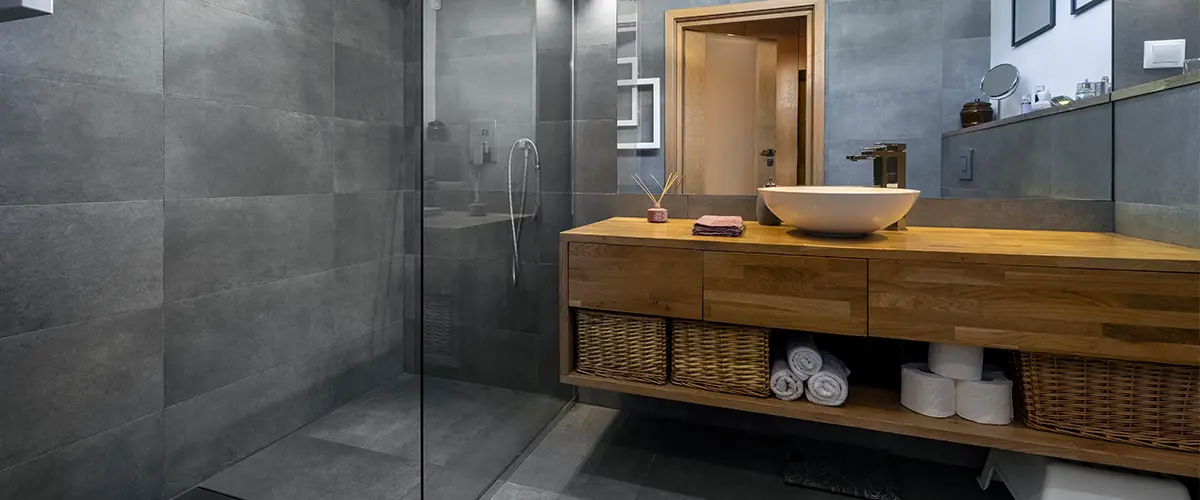 A wood vanity with a walk-in shower made of glass